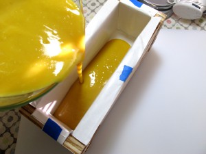 Pouring the soap batter into a wood log mold.