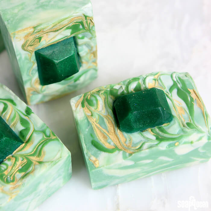 This Emerald Swirl Cold Process Soap Tutorial uses melt and pour embeds and mica painting to create a sophisticated and eye-catching design.