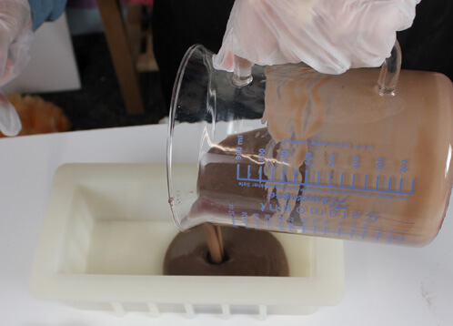 Pouring chocolate brown soap into the silicone mold.