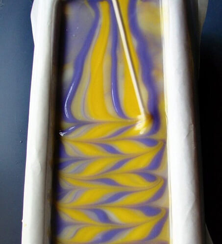 yellow, purple and white swirled soap in a loaf mold.