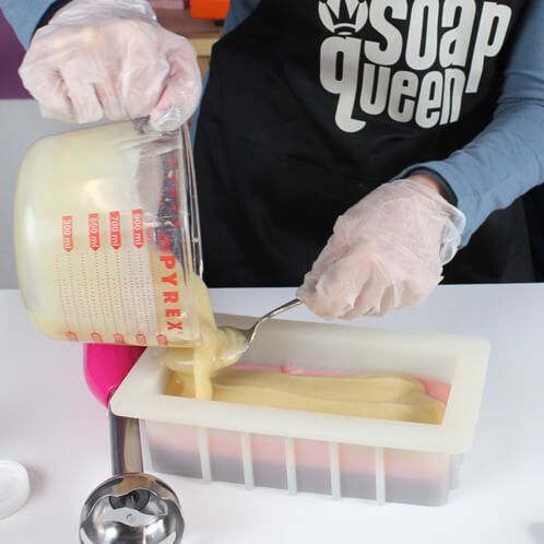 Pouring the final white layer of the neapolitan cold process soap.